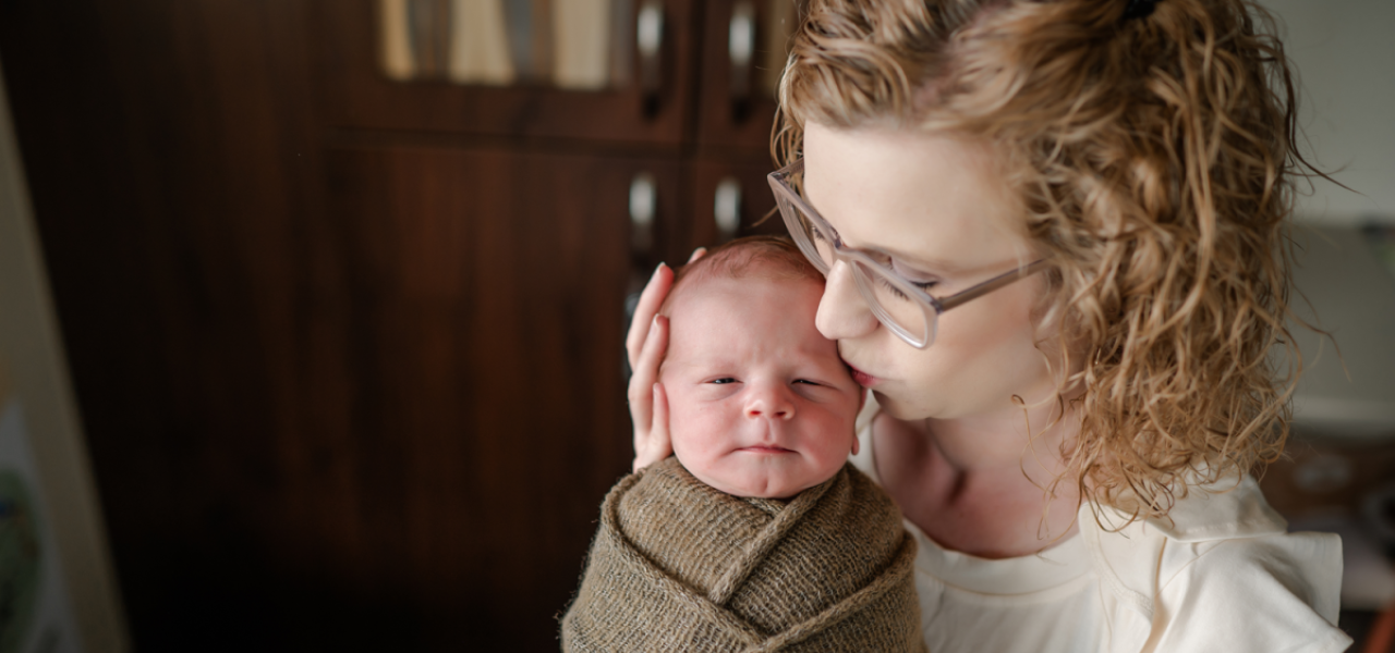 New mother holding baby wrapped in swaddling blanket